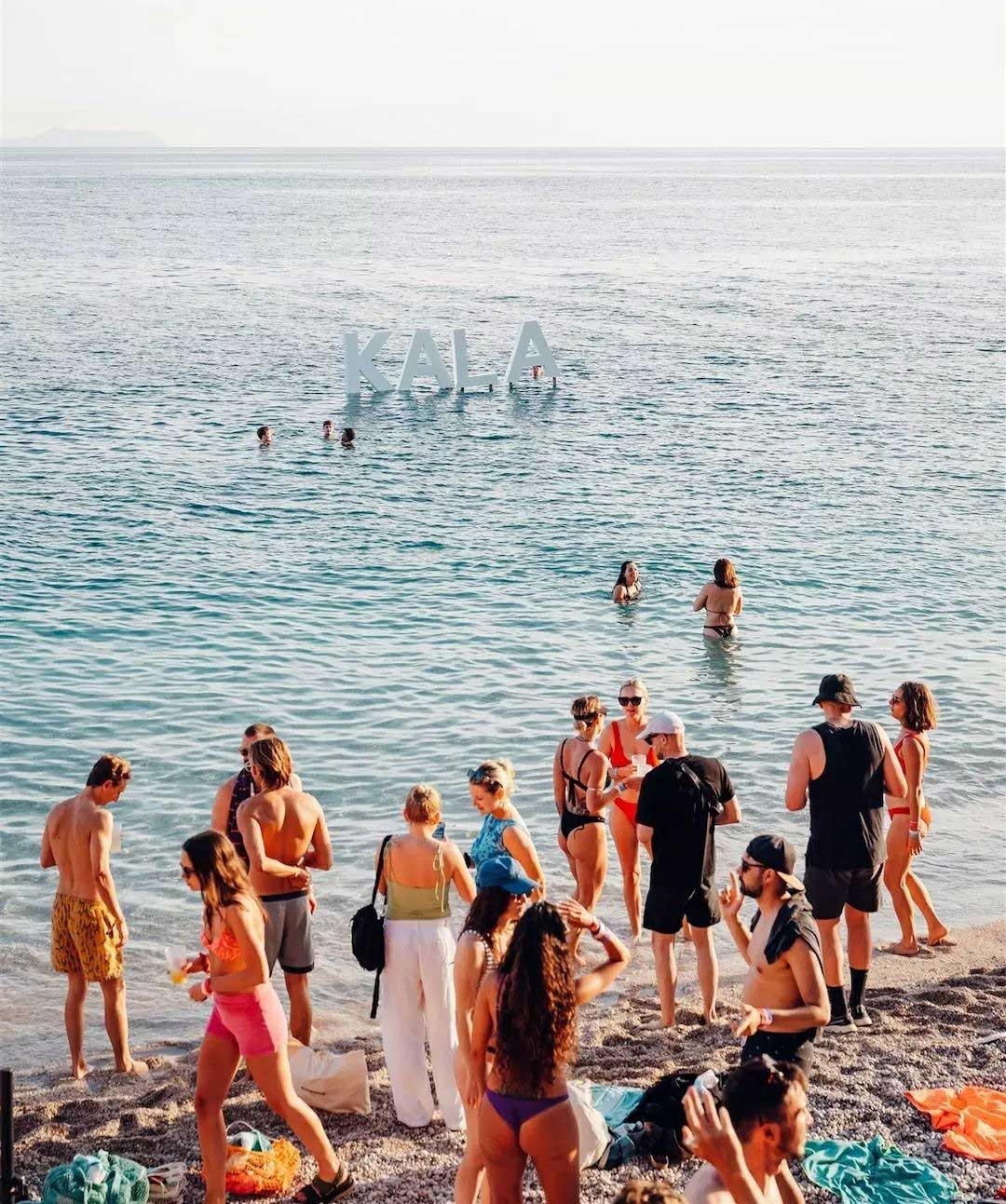 People swim in the sea and dance on the sand at Kala Festival in Albania