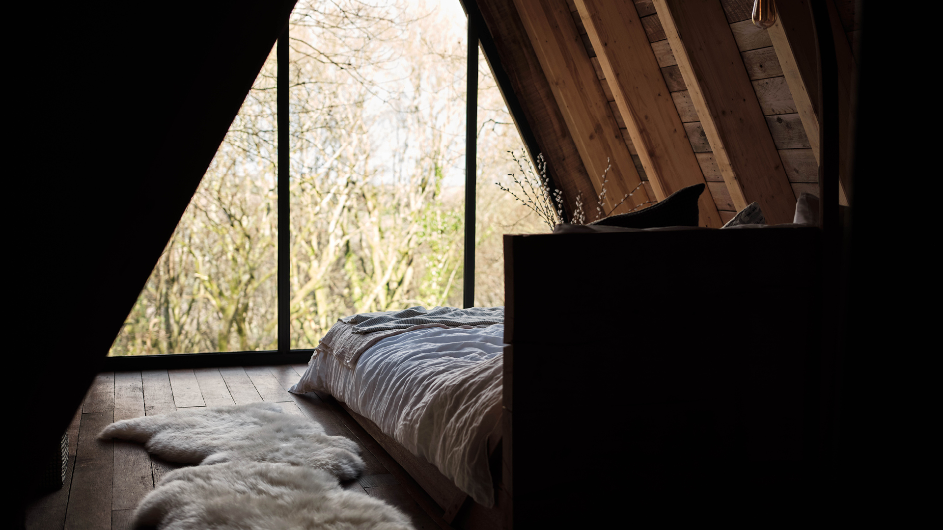 A treehouse bedroom at Hudnalls Hideout with an A-frame window overlooking the forest. Photo by Liz Seabrook