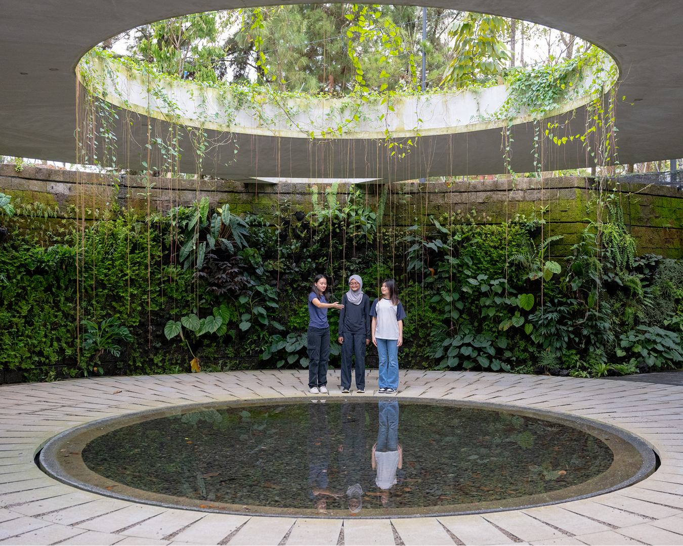 Girls admiring cenote-inspired water feature centrepiece in the Japanese Gardens of Jurong Lake Gardens in Singapore.