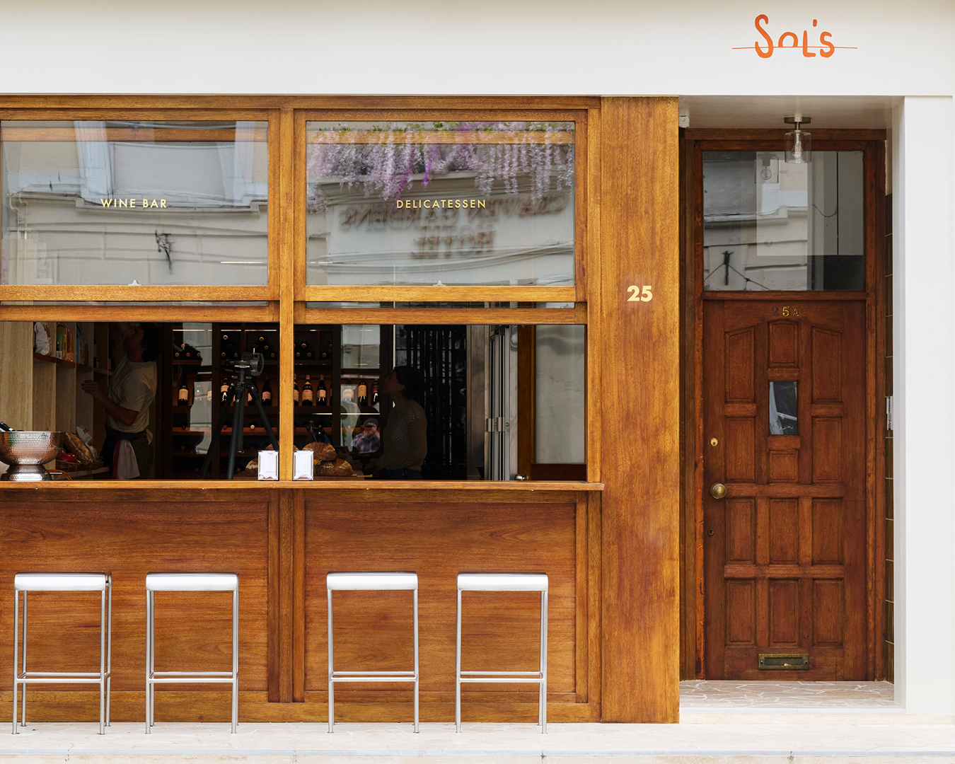 Streetside counter seats frame the exterior of Sol's wine shop and deli in Bayswater