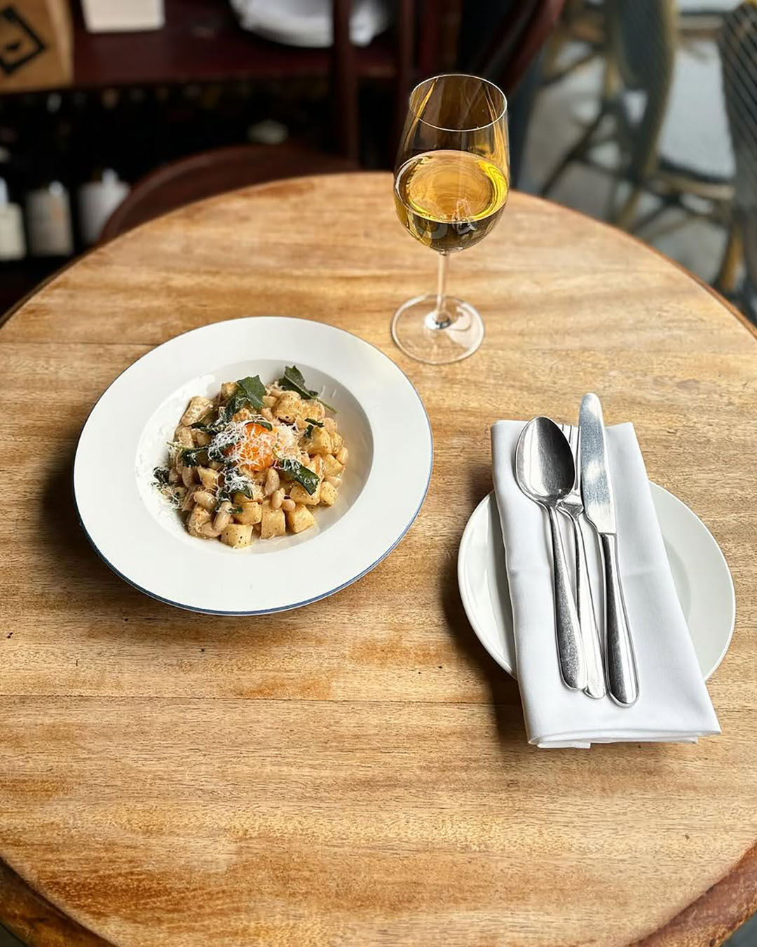 White bean ‘cacio e pepe’ with a glass of wine on a wooden table at The 10 Cases