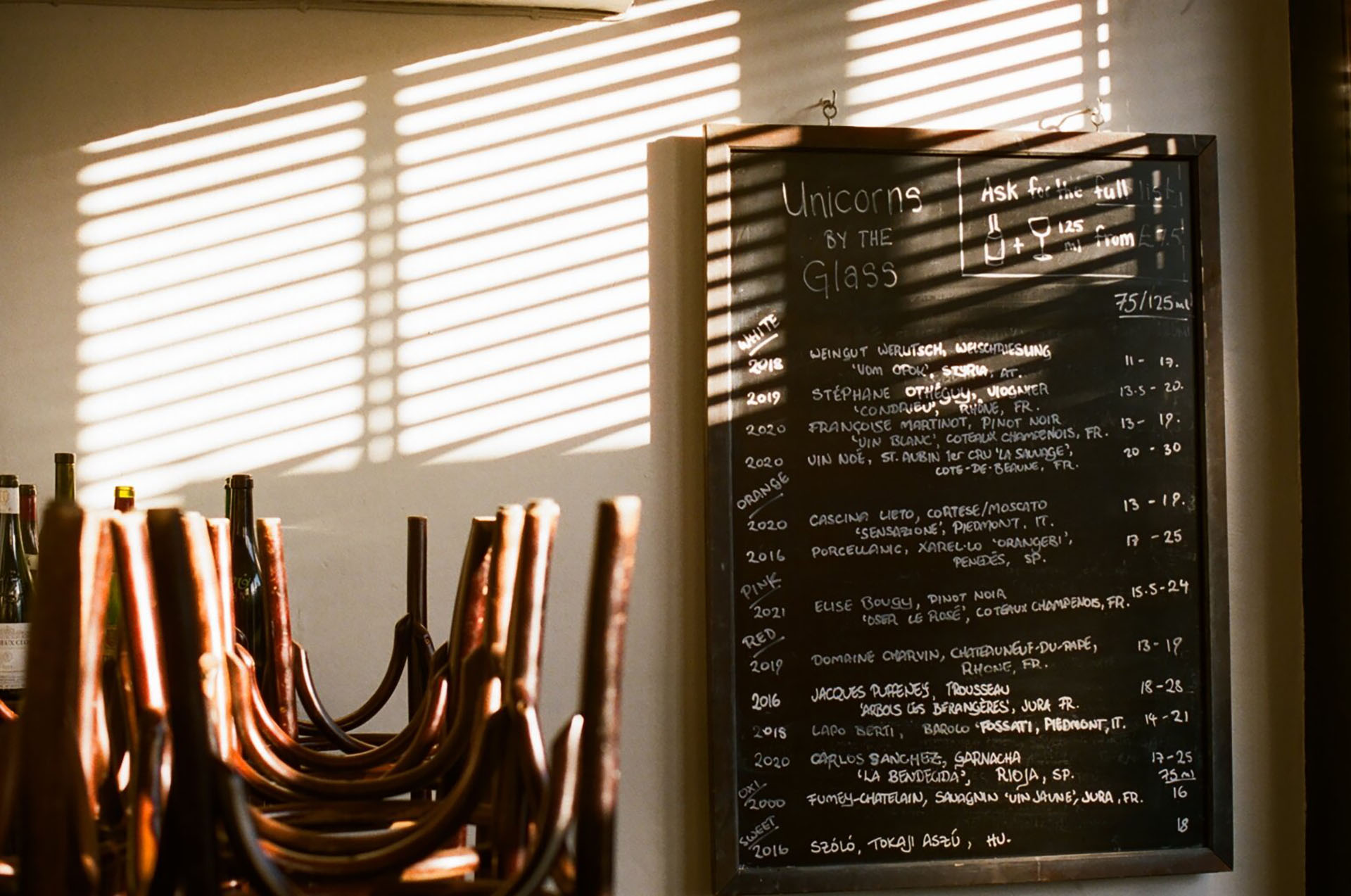 Light streams through a window at Sager + Wild in Hackney, with a wine written on a black board