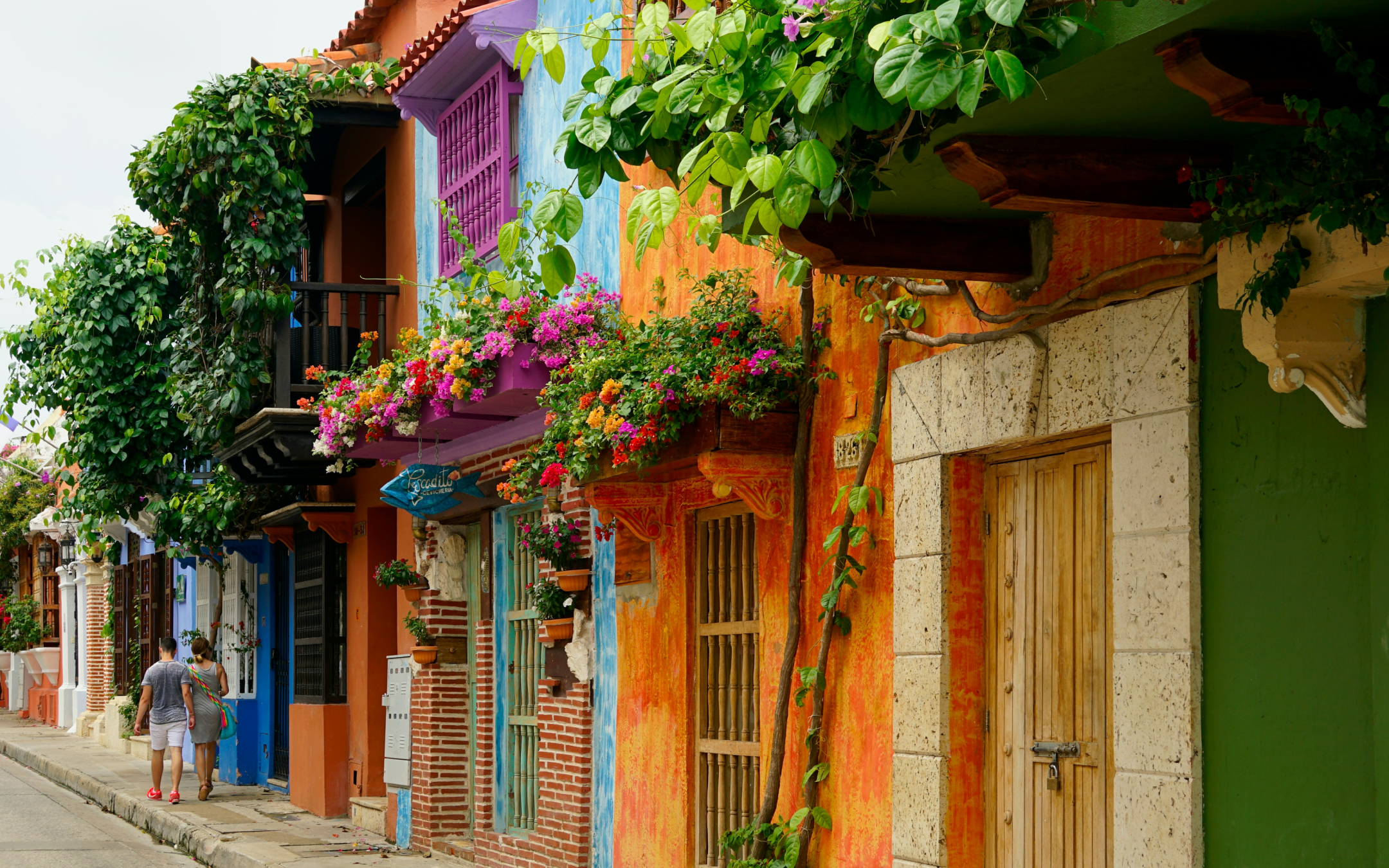 Bold, colourful facades adorned with flowers line a street in Cartagena, Colombia.