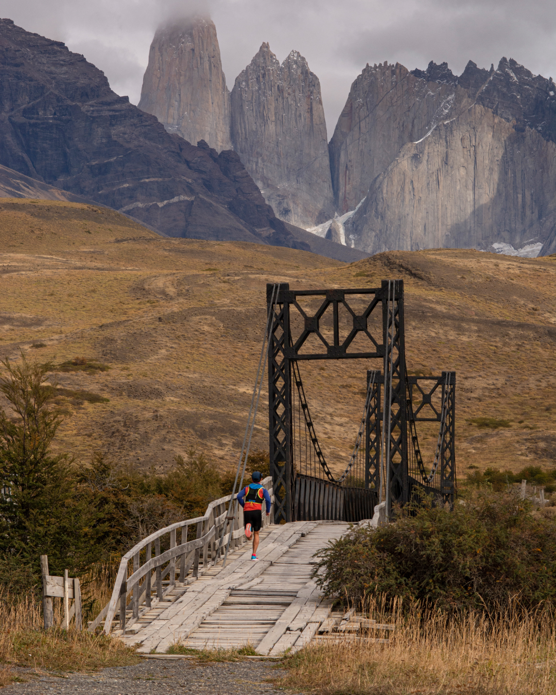 A runner crosses a bridge during the Patagonia Marathon, with views of Torres del Paine in the background. Photo by Patricia Ainol.