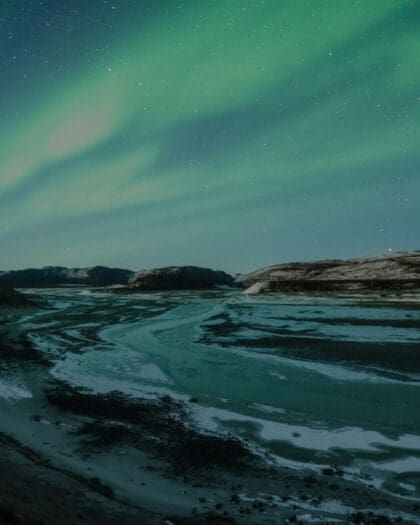 A stunning display of the Northern Lights seen above an icy beach in Kangerlussuaq in Greenland