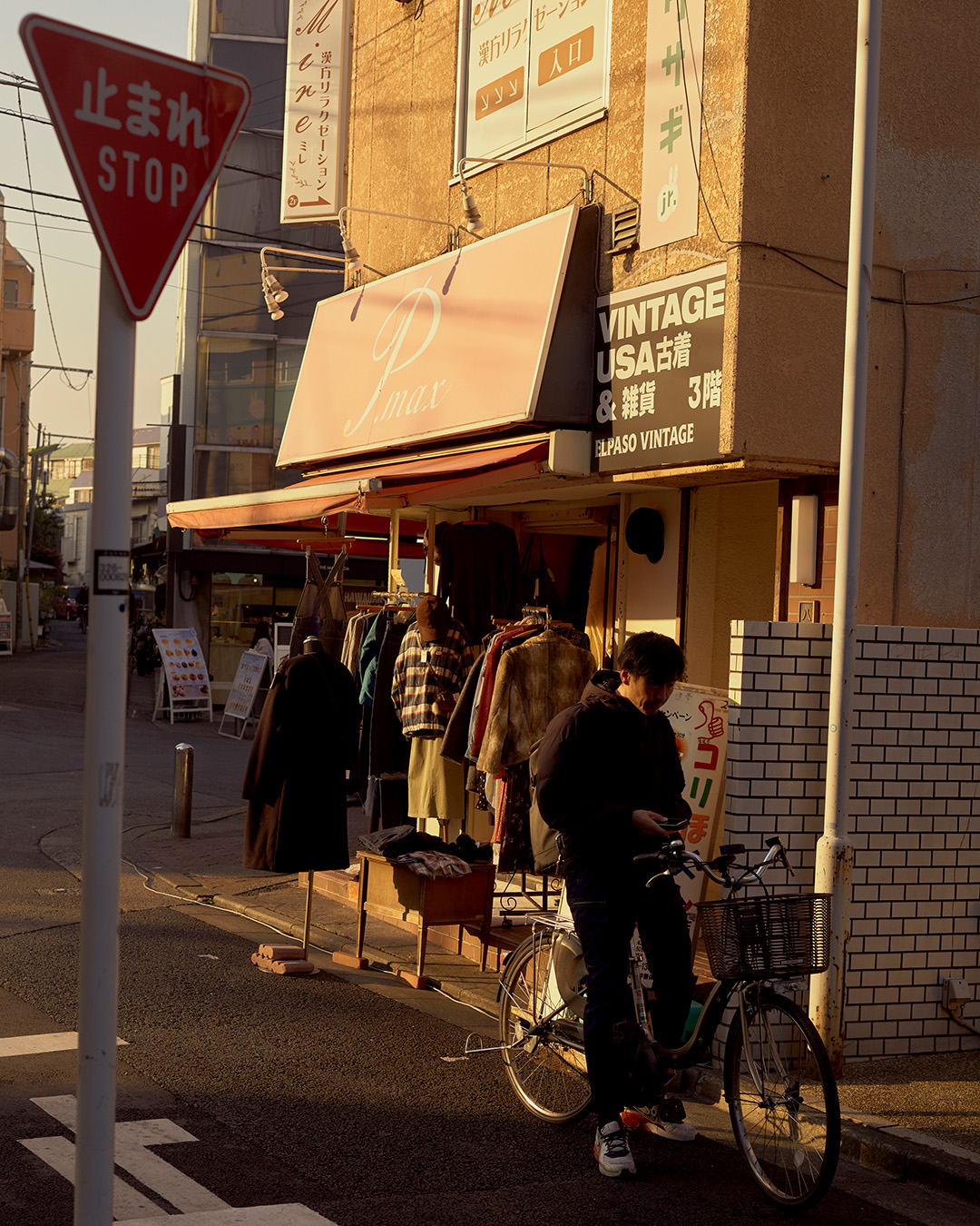 A man on a bicycle outside a second-hand shop in Shimonika, Tokyo